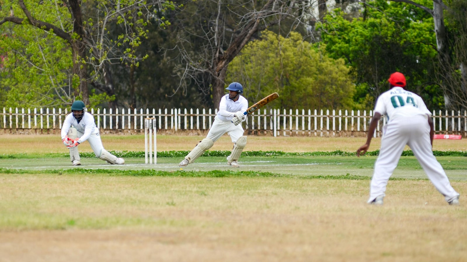 Where does the umpire stand in a cricket match?
